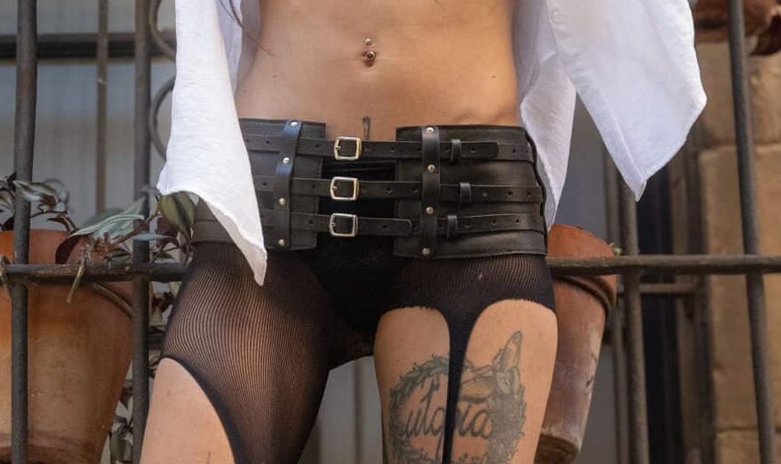Cadera de la modelo llevando puesto un cinturón faja de cuero negro con tres tiras y tres hebillas que cierran el cinturón mismo